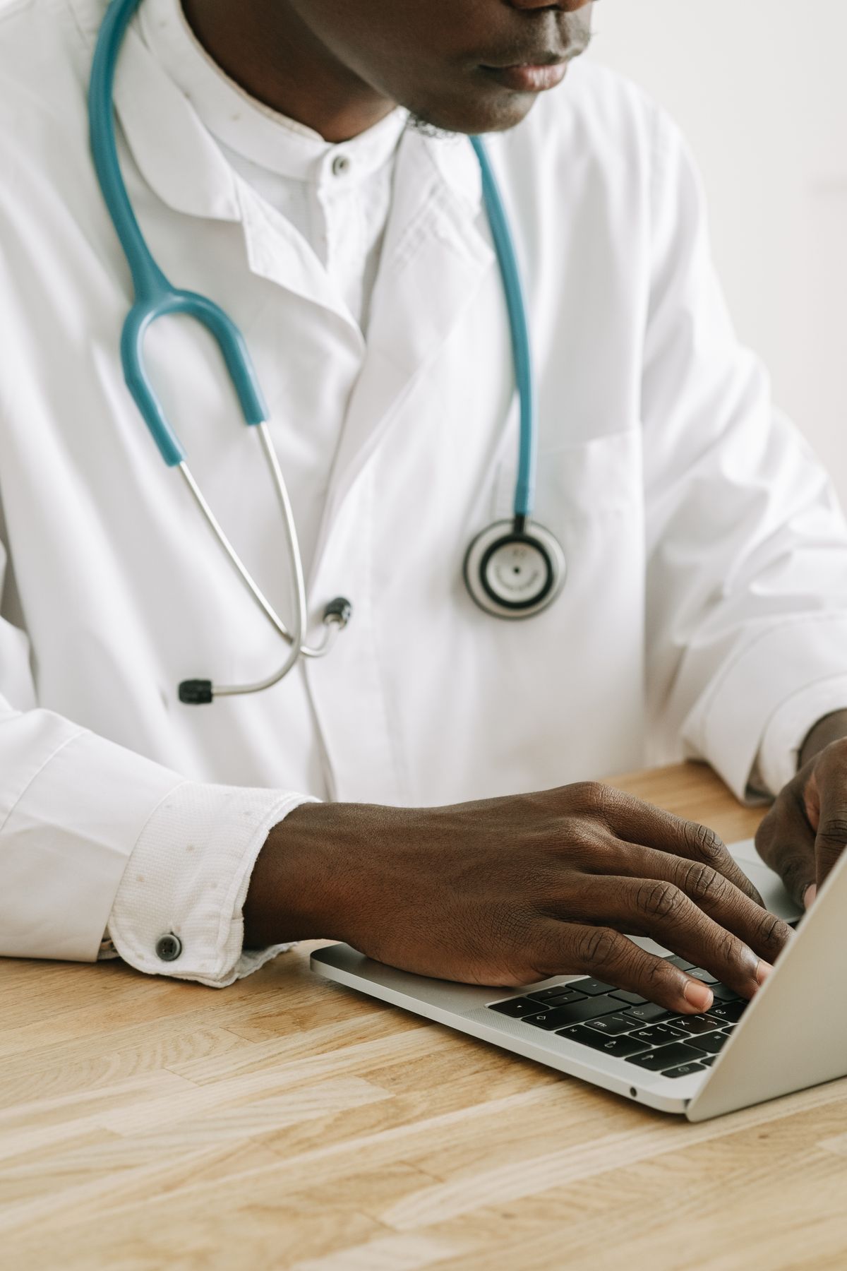 Un médecin en blouse blanche saisit le dossier d'un patient sur un ordinateur portable.